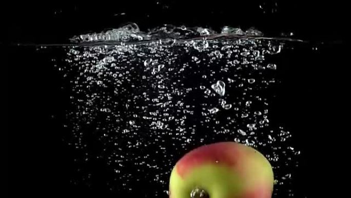 苹果在黑色背景下落入水中的特写镜头。超级慢动作