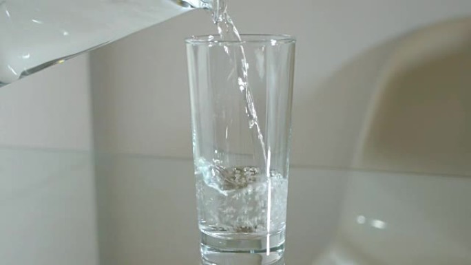 将水罐中的水倒入高高的玻璃杯中