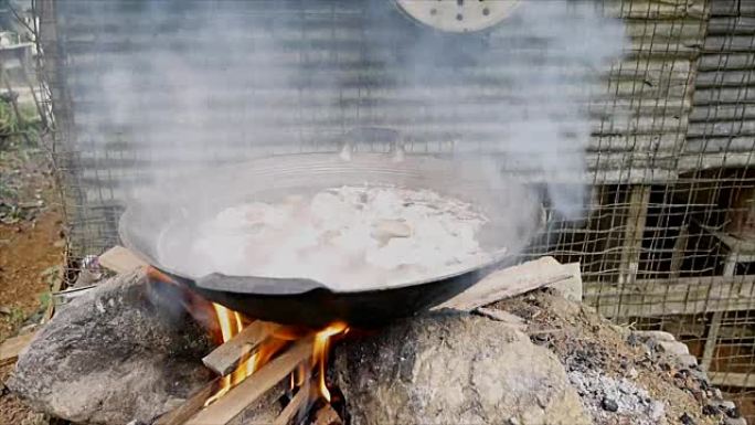 通过在炉子上燃烧柴火在锅中煮沸猪肉