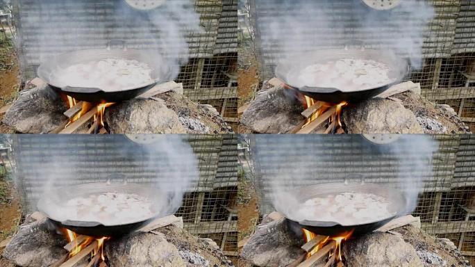 通过在炉子上燃烧柴火在锅中煮沸猪肉