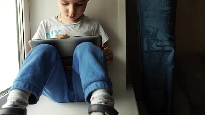 跟踪: 孩子坐在窗台上，使用数字平板电脑