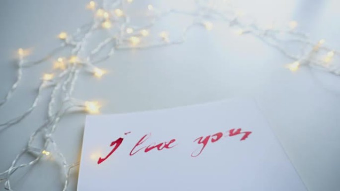拍摄特写的温柔的旗舰上写着“我爱你”的白色床单，桌上闪烁的花环