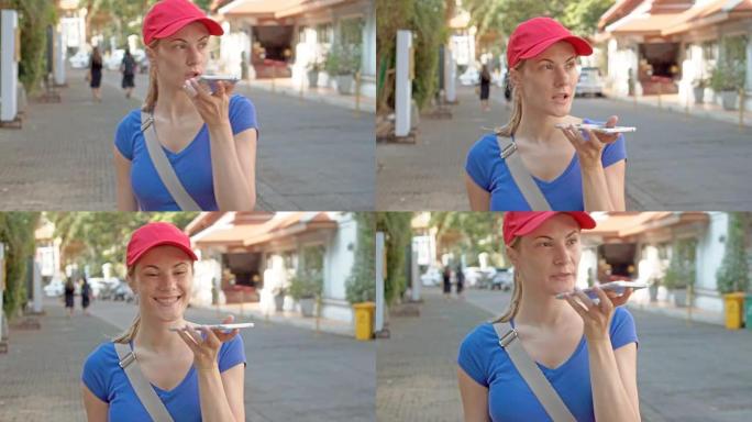 戴着红帽的漂亮女人游客用智能手机走在街上，和朋友聊天