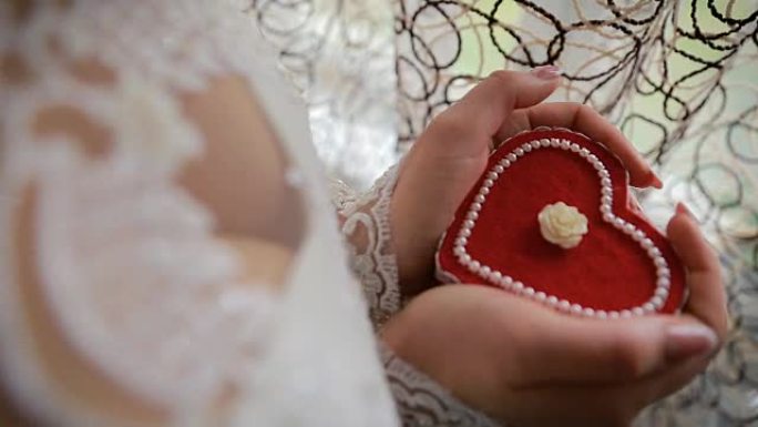 美女手握心形订婚戒指盒。新娘手里拿着一个心形礼品盒
