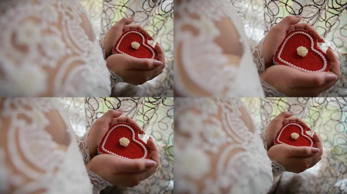 美女手握心形订婚戒指盒。新娘手里拿着一个心形礼品盒