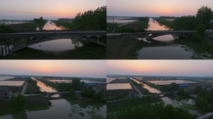 女生站在乡村小桥上在夕阳落日下挥手