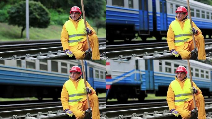 铁路工人穿着黄色制服，手拿铁铲坐在铁轨上