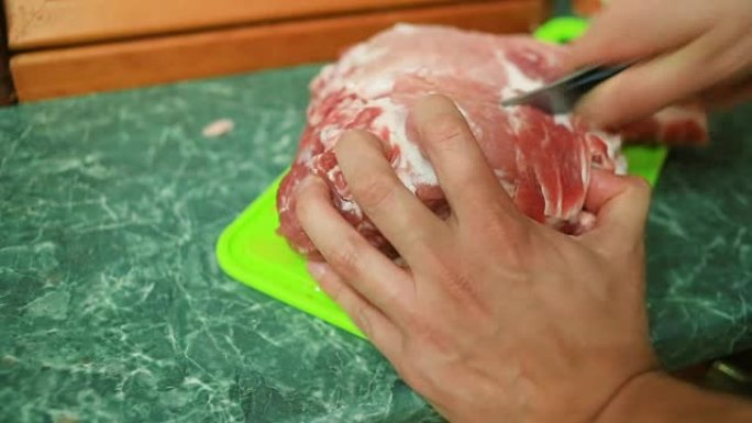 雄性手在砧板上的牛排上切生肉。特写。