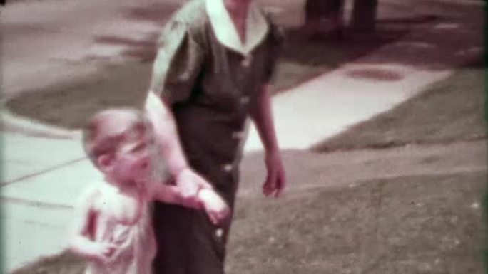 1937: 奶奶走在郊区的蹒跚学步的男孩，老爷车驶过。