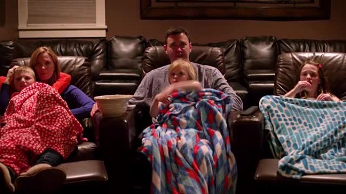 一家人在家庭影院看电影，用毯子和爆米花