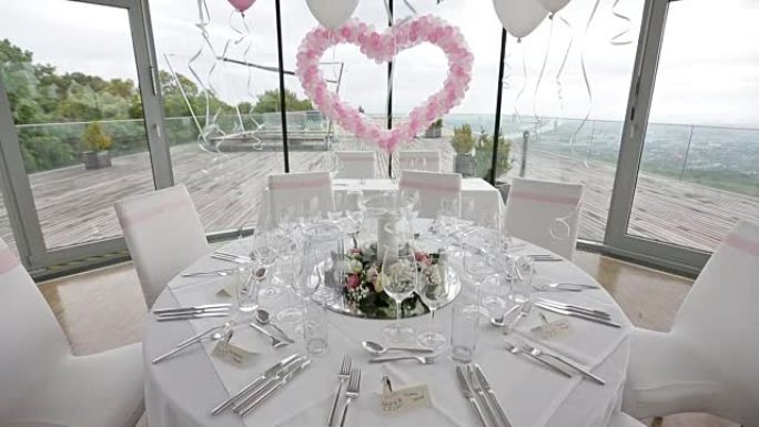 餐桌设置的fof客人。用粉色气球和鲜花装饰的豪华婚礼大厅