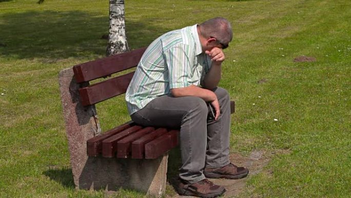沮丧的人在公园的长凳上哭泣
