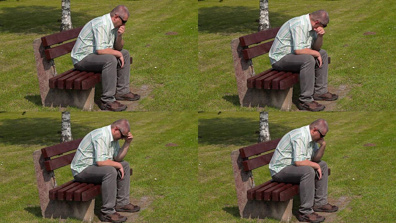沮丧的人在公园的长凳上哭泣