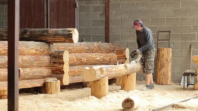男人为未来的小木屋切断了光束电锯。木结构建筑工程