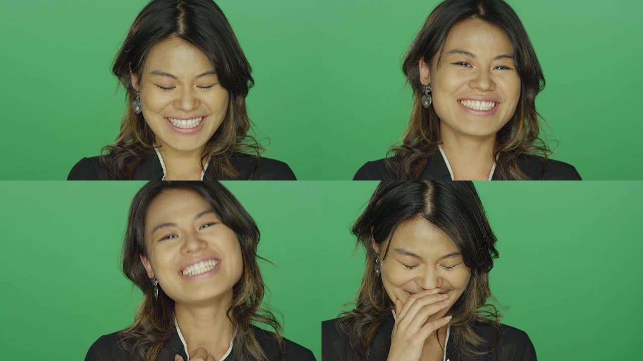 年轻的亚洲女性在绿屏工作室背景下微笑和大笑