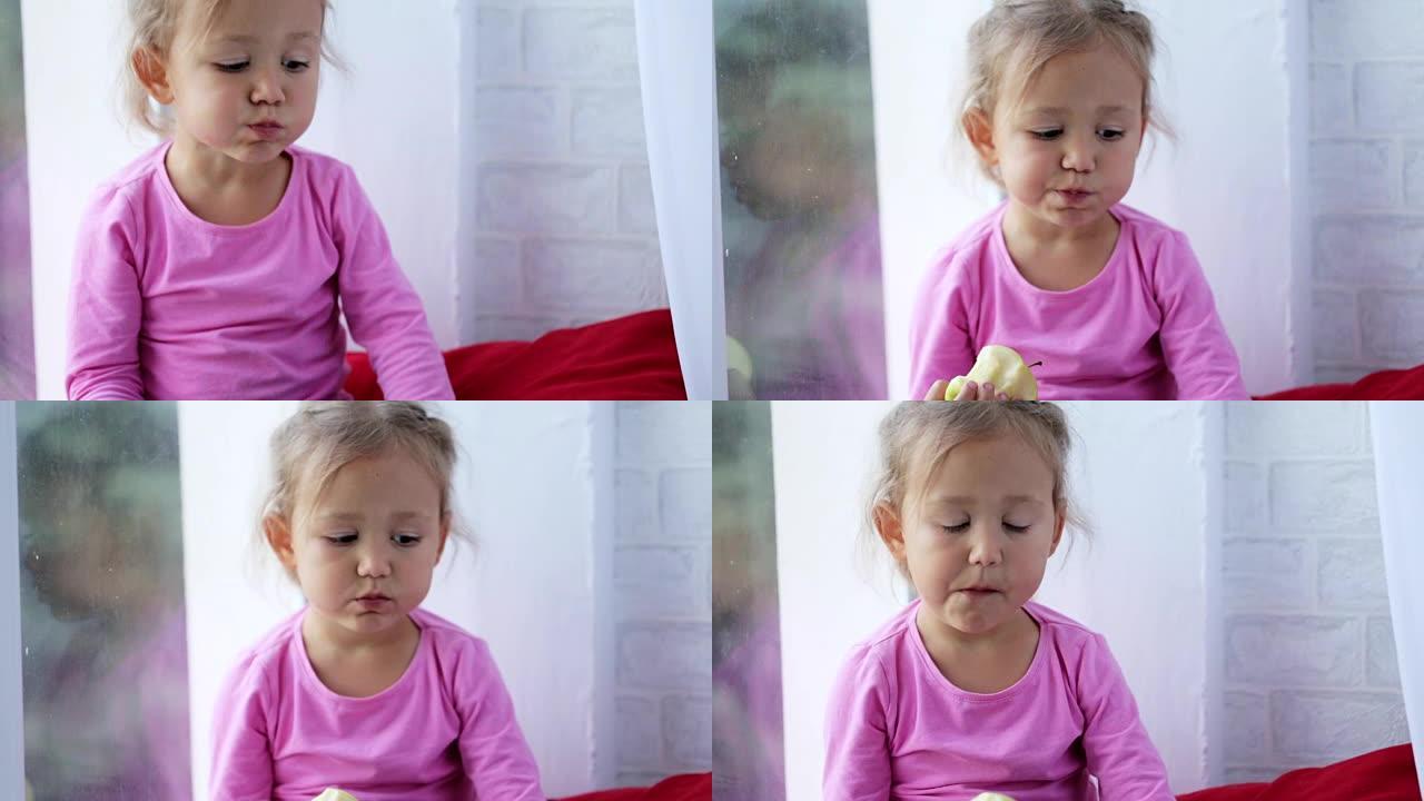 有趣可爱的小女孩坐在窗台上吃苹果的肖像。