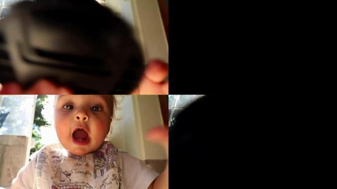宝贝想放相机镜头盖。揭示黑暗到光明的婴儿。顽皮的婴儿幼儿玩相机