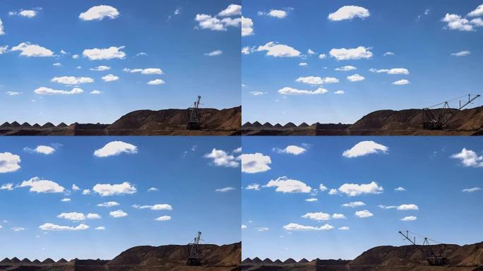 在蓝天和移动的云的背景下，广阔的镜头与拖曳挖掘机装载矿石的矿井。铝土矿的猎物。