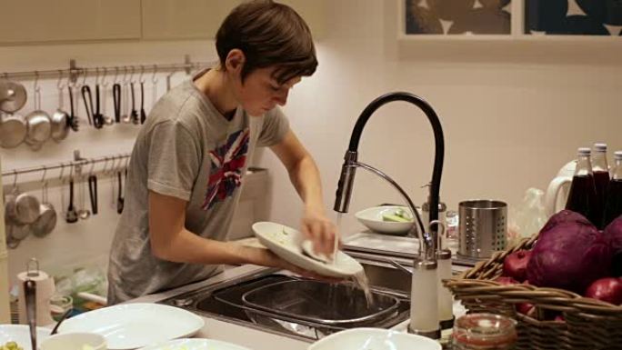 十几岁的男孩在水槽里洗餐盘