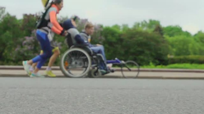 意志力和友谊的概念。残疾人运动员在助手们的陪同下参加运动轮椅的比赛。慢动作。循环