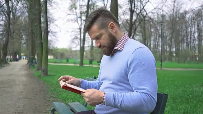 男子坐在公园读书的长凳上，steadycam射击