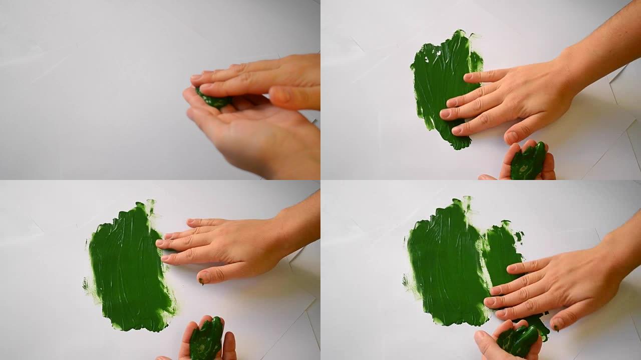 绿色油漆通过白纸涂抹双手