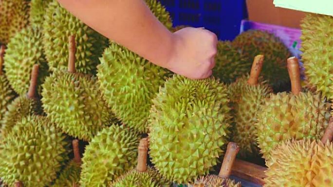一个小贩挑选榴莲水果卖给当地市场街的顾客。榴莲在东南亚被许多人视为水果之王。