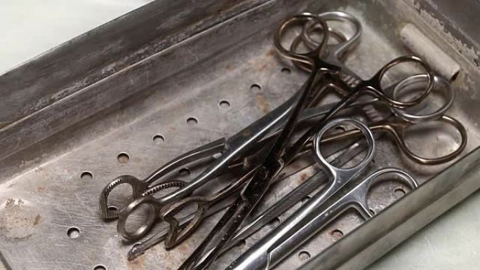 钢制托盘中的旧镊子和医用剪刀。