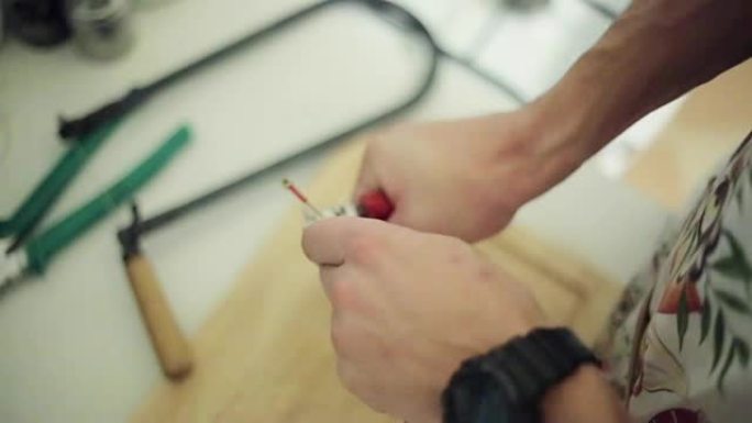 男人用手剪断，用红色钳子剪断长电线。特写