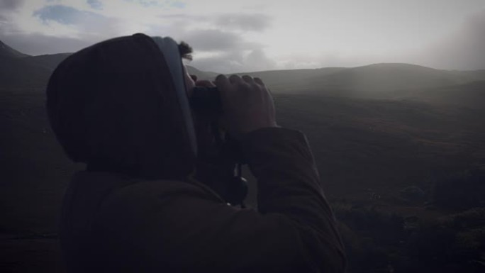 用双筒望远镜看着爱尔兰村庄的男子的4k镜头