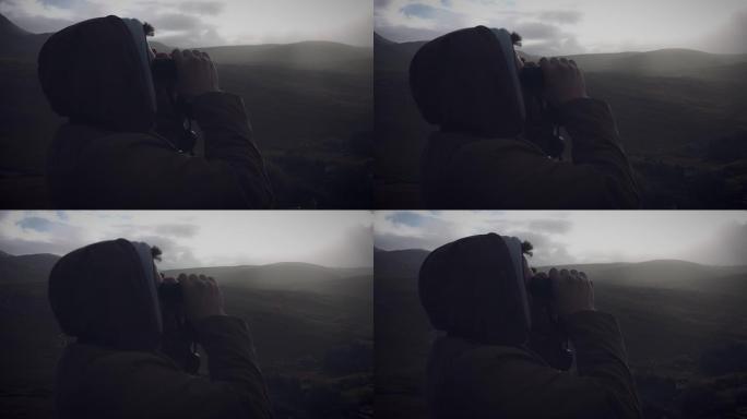 用双筒望远镜看着爱尔兰村庄的男子的4k镜头