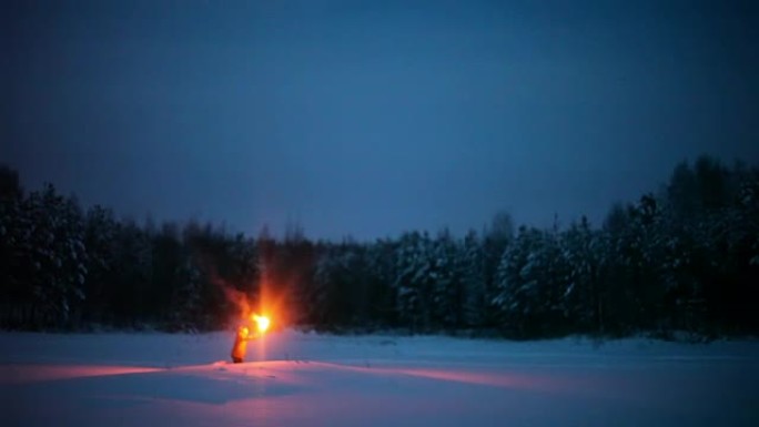 一个晚上拿着火炬的家伙在冬天的森林里穿过雪堆