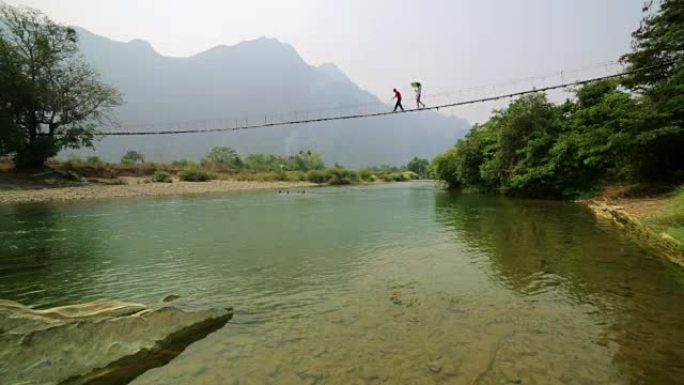 老挝万盛竹吊桥上过河的人