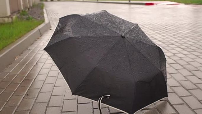 黑色雨伞在雨中躺在马路上。