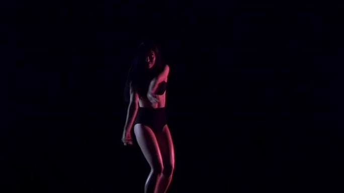 性感的女人跳舞，黑暗的背景。缓慢的运动。