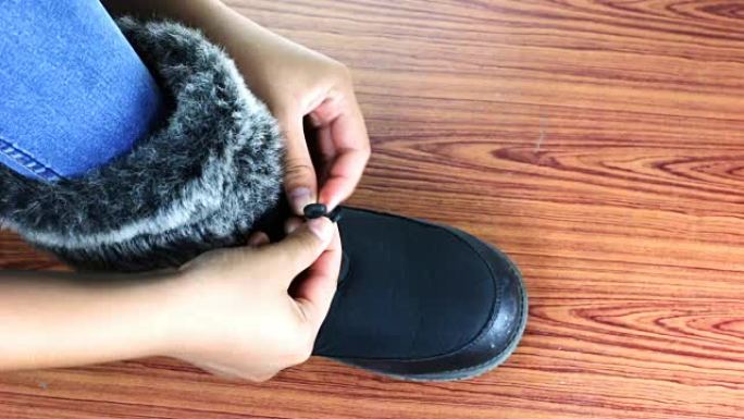 一个小女孩系着他的冬靴的特写镜头。