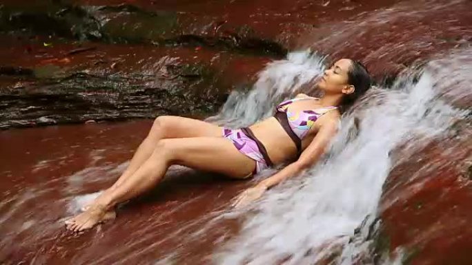 躺在瀑布河里的性感比基尼女孩