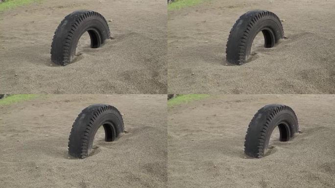埋在沙子里的旧车轮。平行滑动视图。