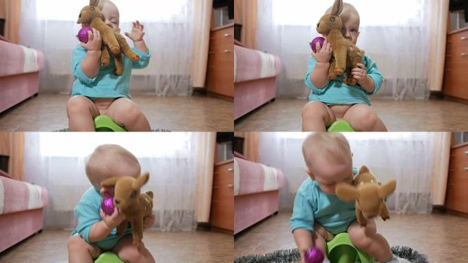 迷人的婴儿坐在锅上玩泰迪鹿。在新年舞会和圣诞树装饰的手中。家庭新年的概念