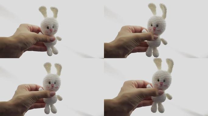 一只展示玩具兔子的雌性手。