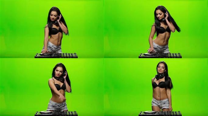 女孩DJ转盘和舞蹈扭转。绿色的屏幕。慢动作