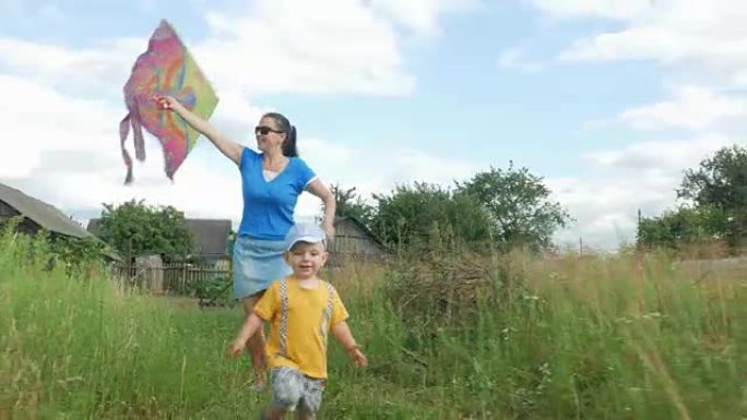 一位年轻的母亲带着婴儿在夏天在绿色的田野里发射空中风筝。母亲做得不好。儿子很开心