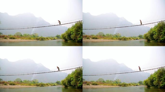 老挝穿越危险竹吊桥的旅游妇女