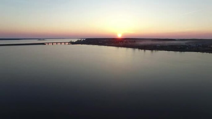 日落时分，在带桥梁的大冻湖上飞行，空中飞行。