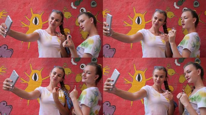 女孩的Selphi在涂鸦的背景下手臂上有旋转器，女友用玩具在手机上拍照以减轻压力