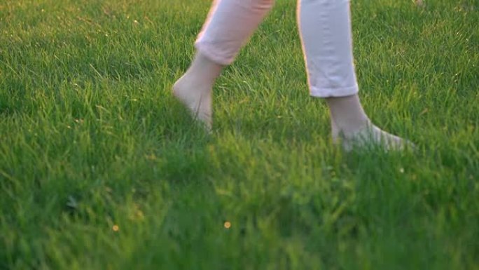赤脚的女人只在绿色的草地上行走