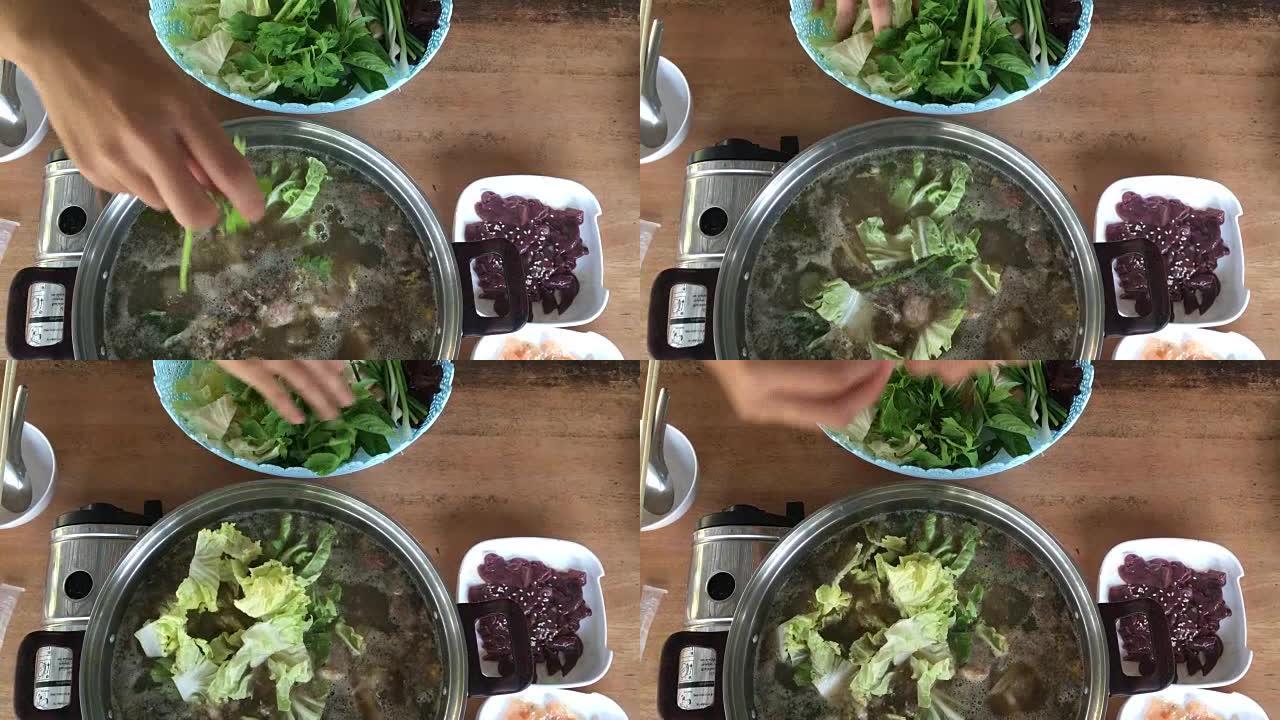 煮沸的寿喜烧锅加入蔬菜