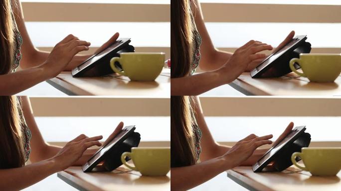 在露天咖啡馆使用平板电脑的特写女性双手。