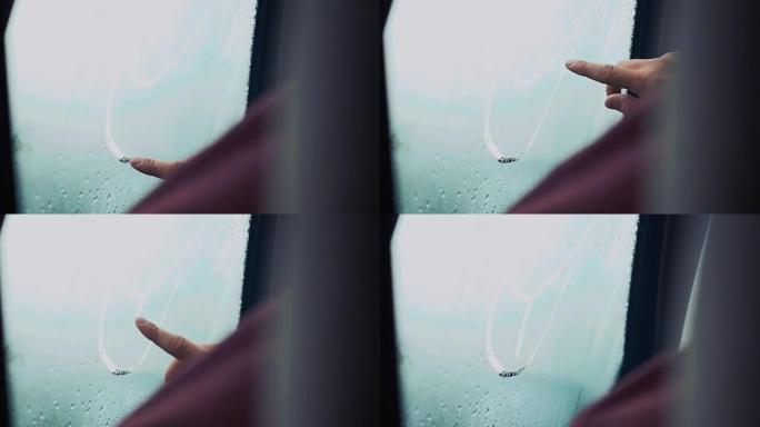 男人用一根手指在车窗上画舌头。外面有雨的天气。滴