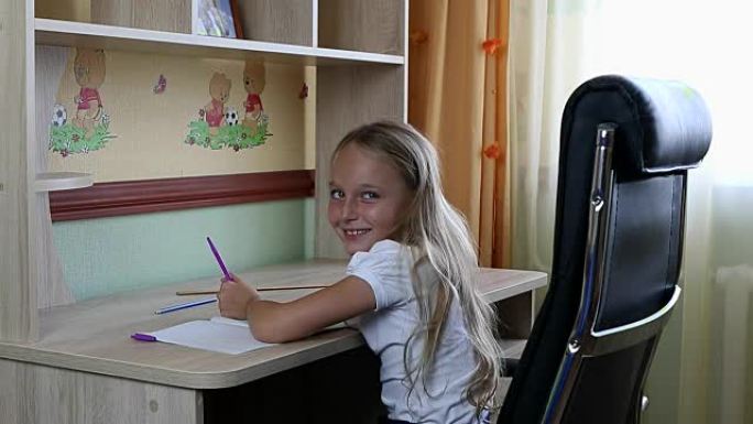 左撇子女孩坐在桌子旁的椅子上，用笔在纸笔记本上写字。回到学校。年轻的高加索女孩微笑着。坐在桌子旁边。